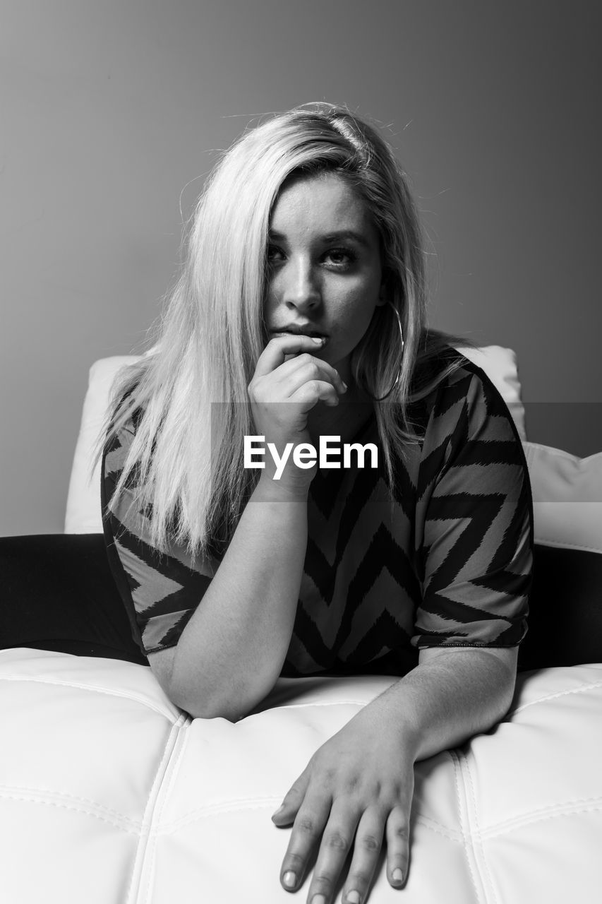 Portrait of young woman sitting on bed at home