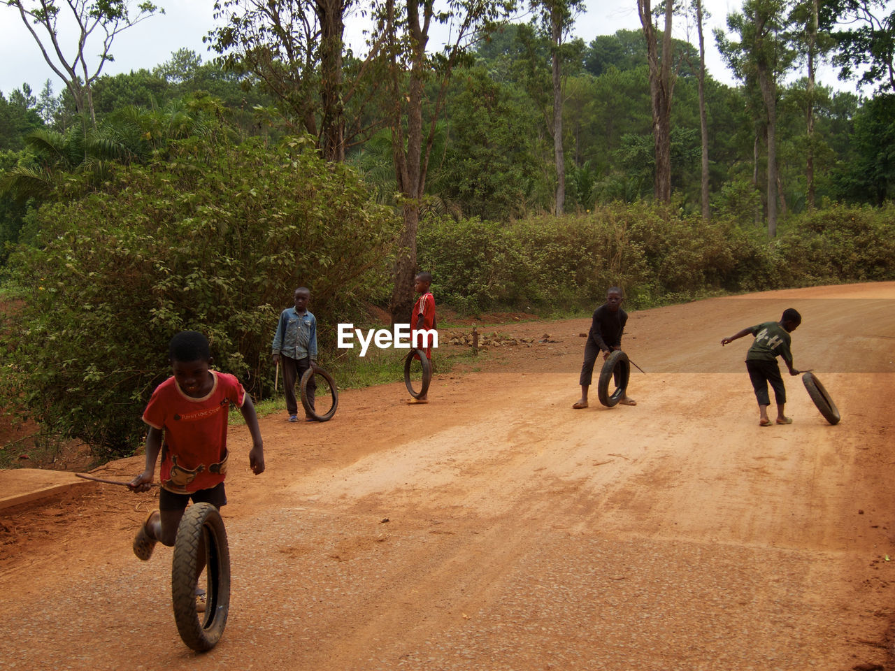 REAR VIEW OF PEOPLE PLAYING ON THE ROAD