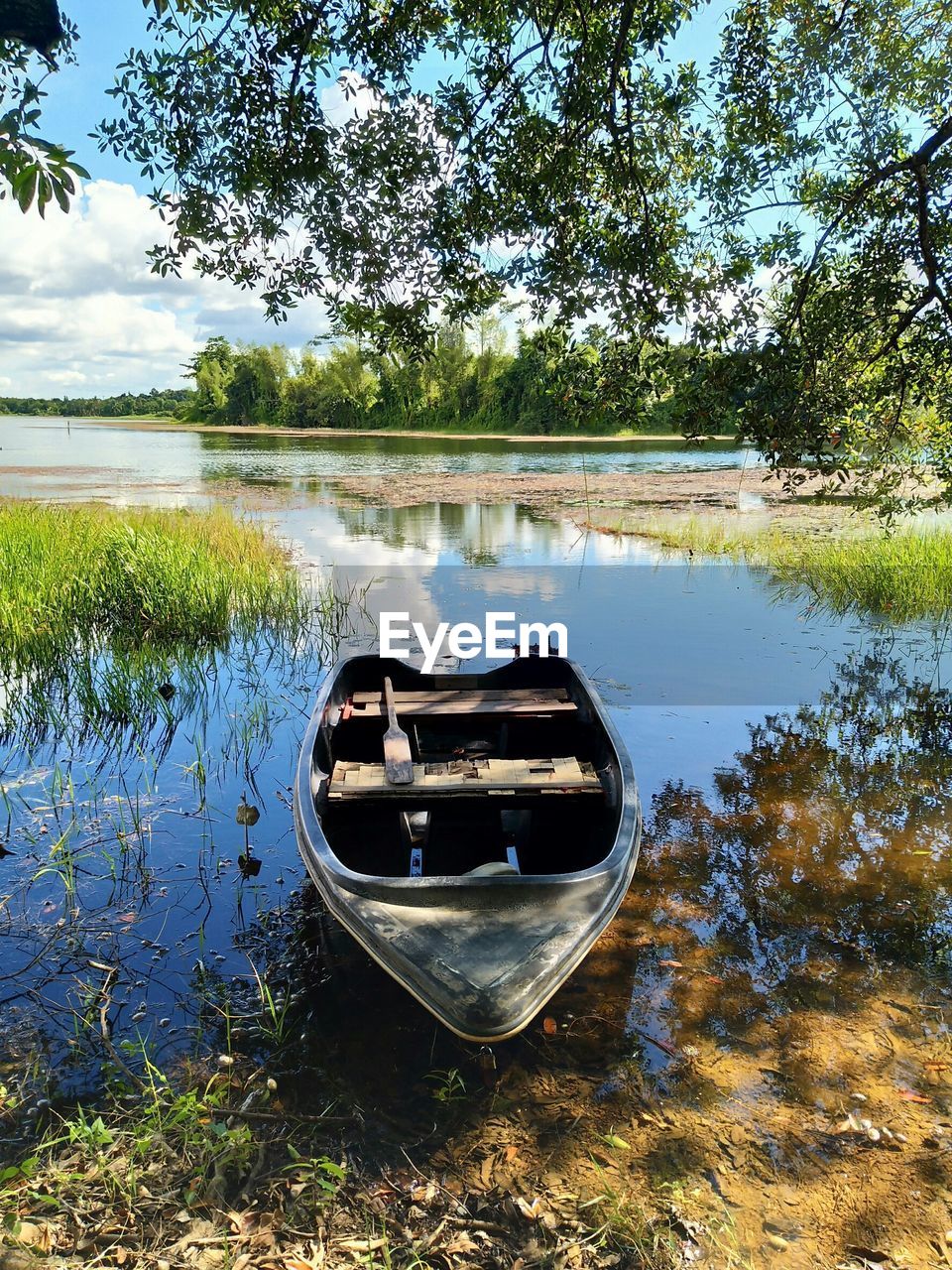 Boat moored on lake against trees