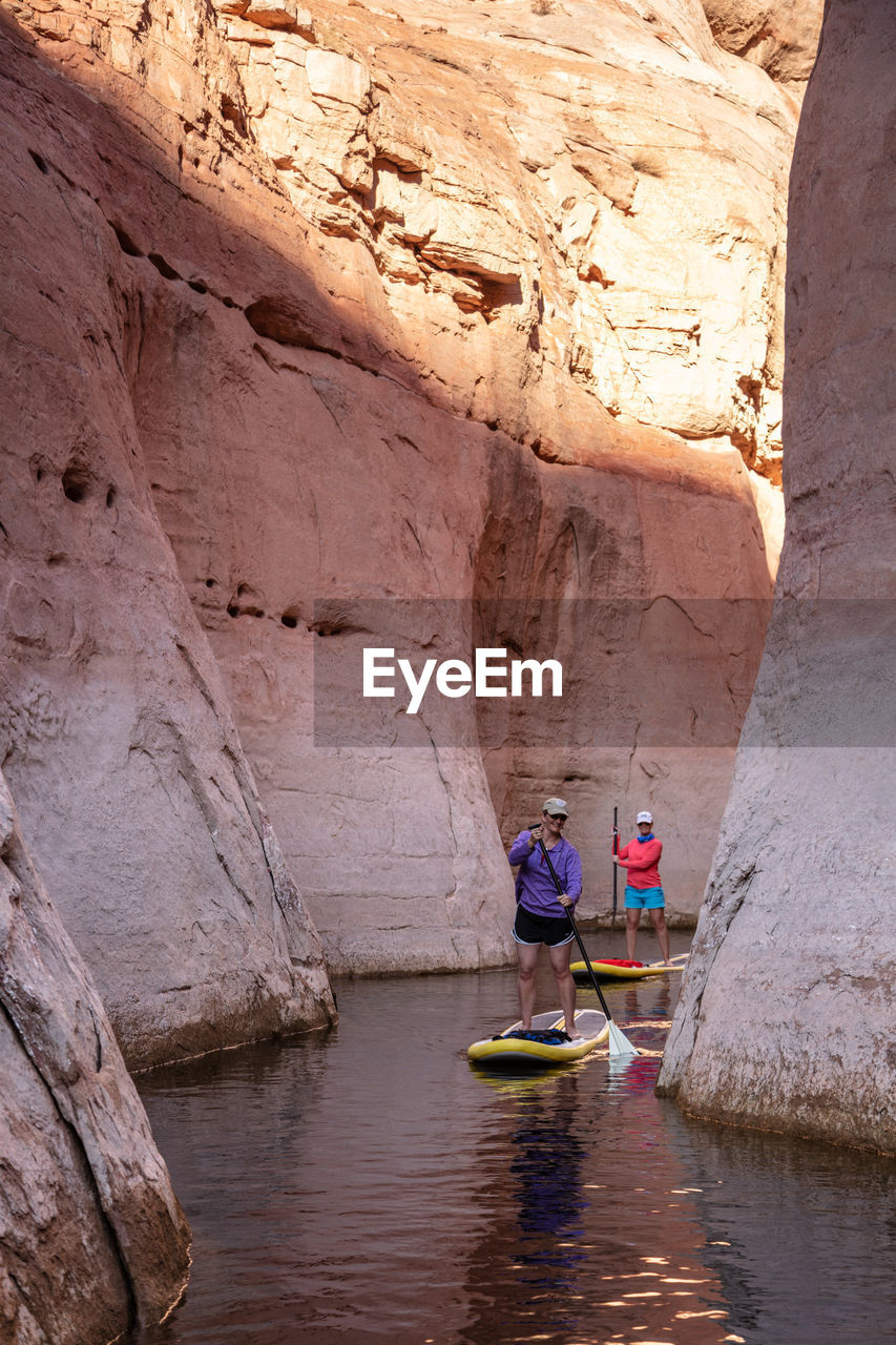 REAR VIEW OF PEOPLE IN BOAT ON ROCK FORMATION