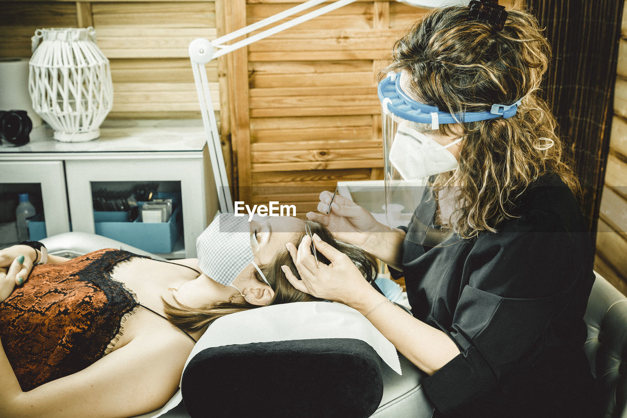 Beautician working with mask and protective screen for the virus covid