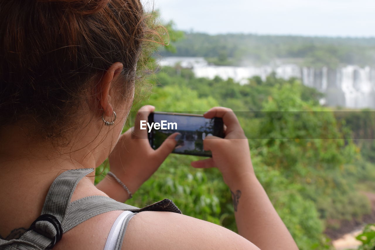 MIDSECTION OF WOMAN USING MOBILE PHONE OUTDOORS