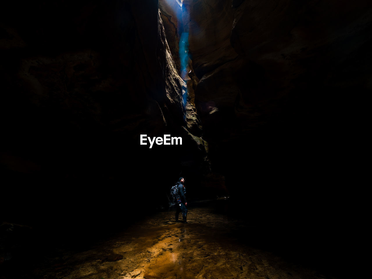 REAR VIEW OF MAN WALKING ON CAVE