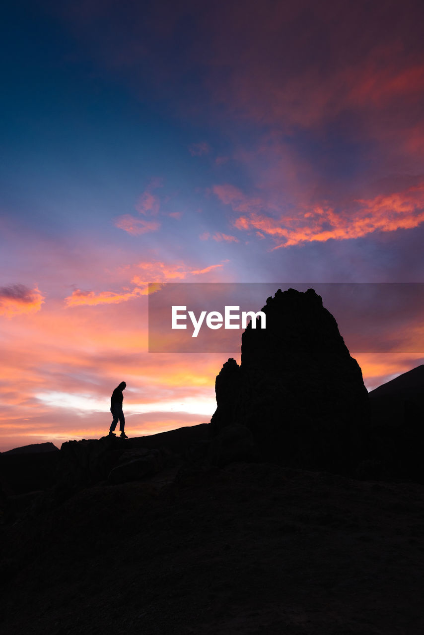 Silhouette of a young girl walking on rocks an amazing sunset