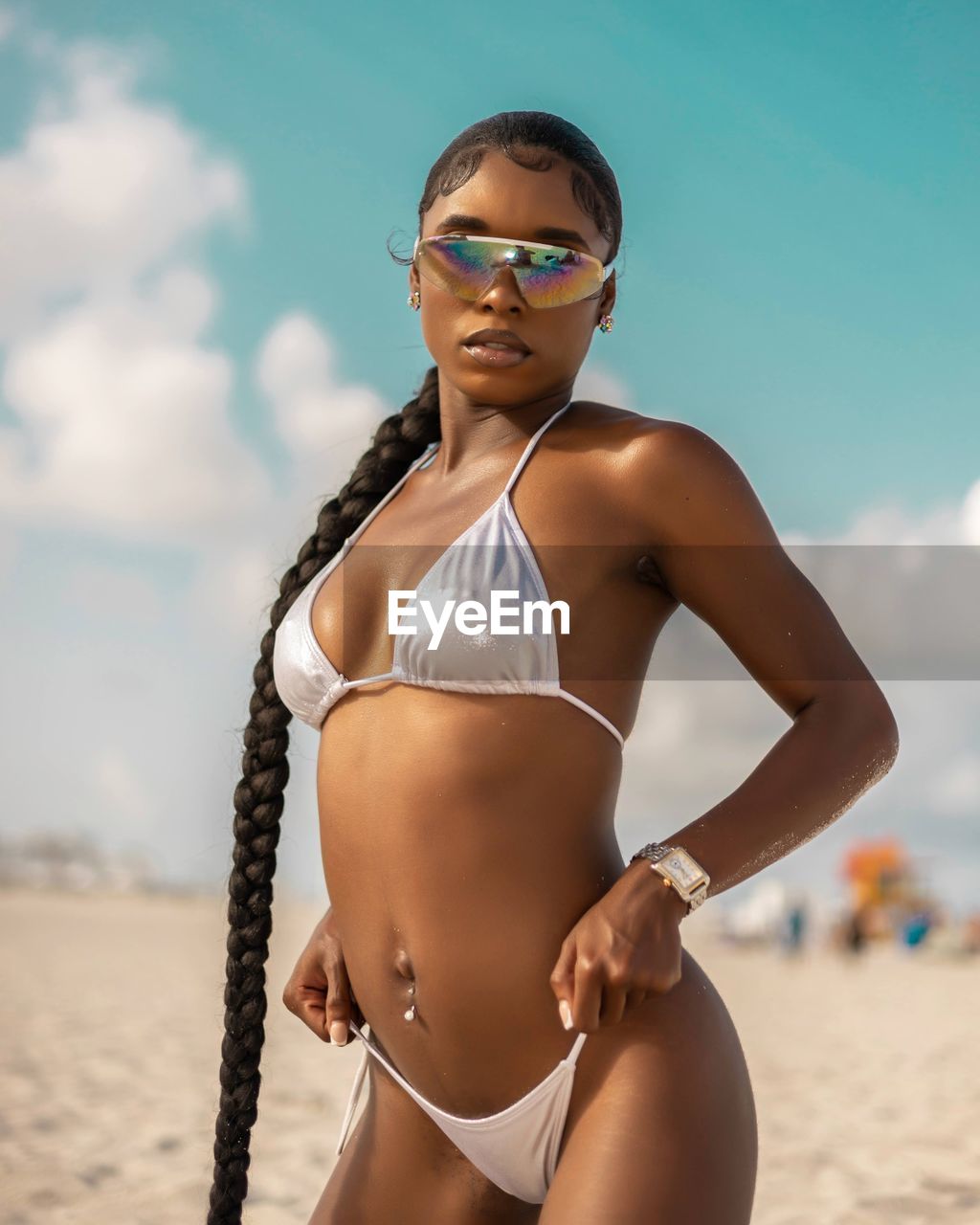 portrait of woman wearing sunglasses while standing at beach against sky