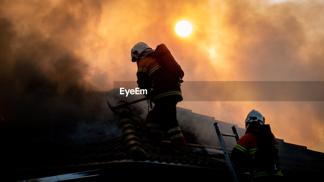 Firefighter working in roof in sunset