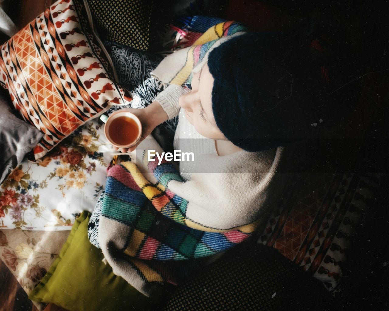 Woman having coffee while sitting on bed at home