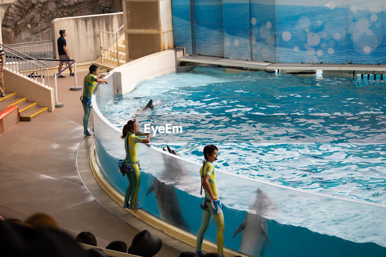 HIGH ANGLE VIEW OF PEOPLE BY SWIMMING POOL