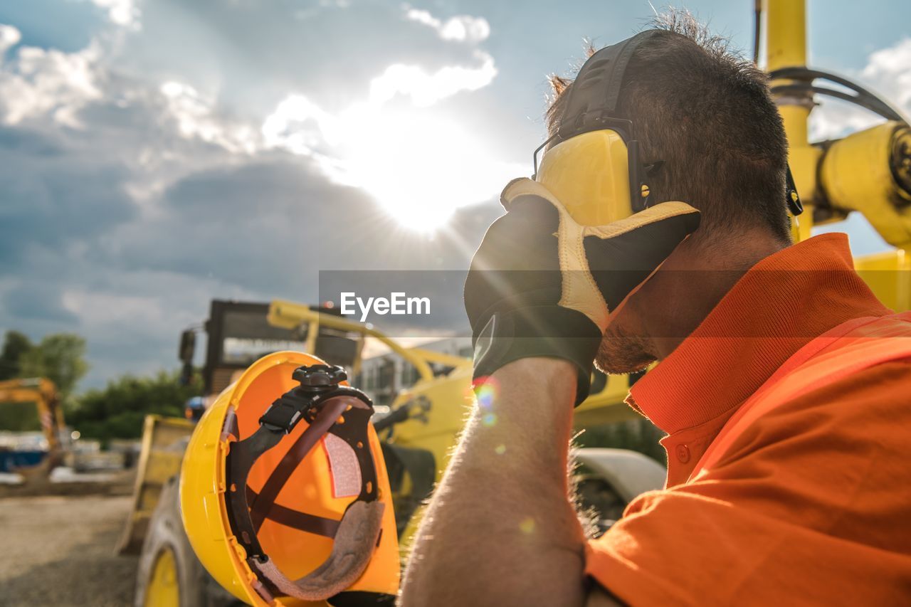 Side view of operator wearing headset by vehicle at construction site