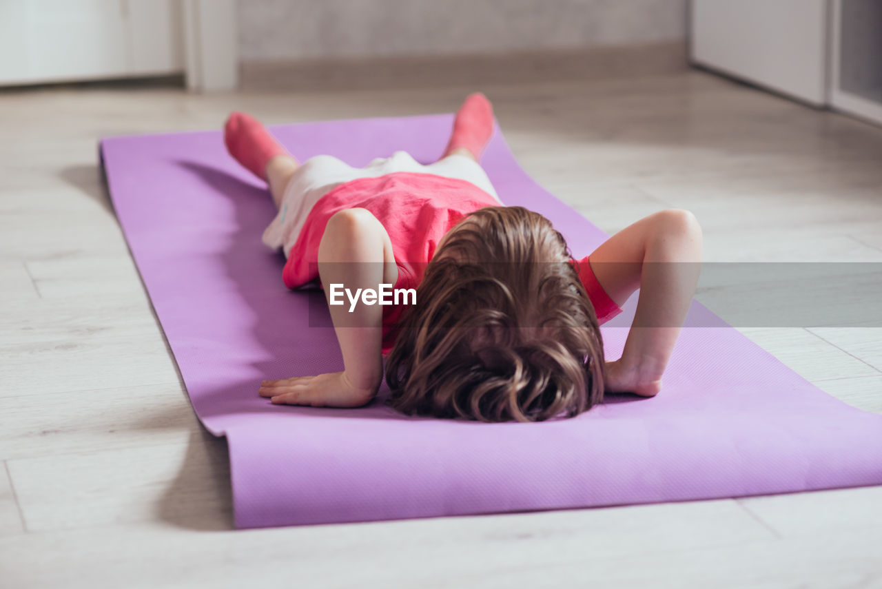 Child lies on the mat to do the exercise. the concept of health, sports, learning online
