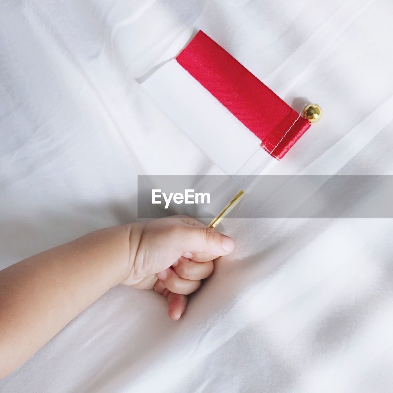 HIGH ANGLE VIEW OF PERSON HAND HOLDING RED PAPER WITH TATTOO