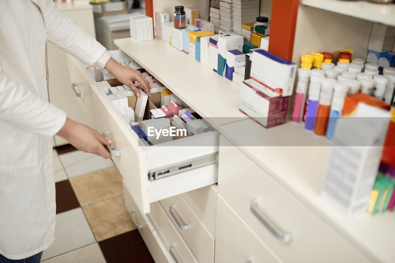 Pharmacist arranging medicines in drawer at pharmacy store