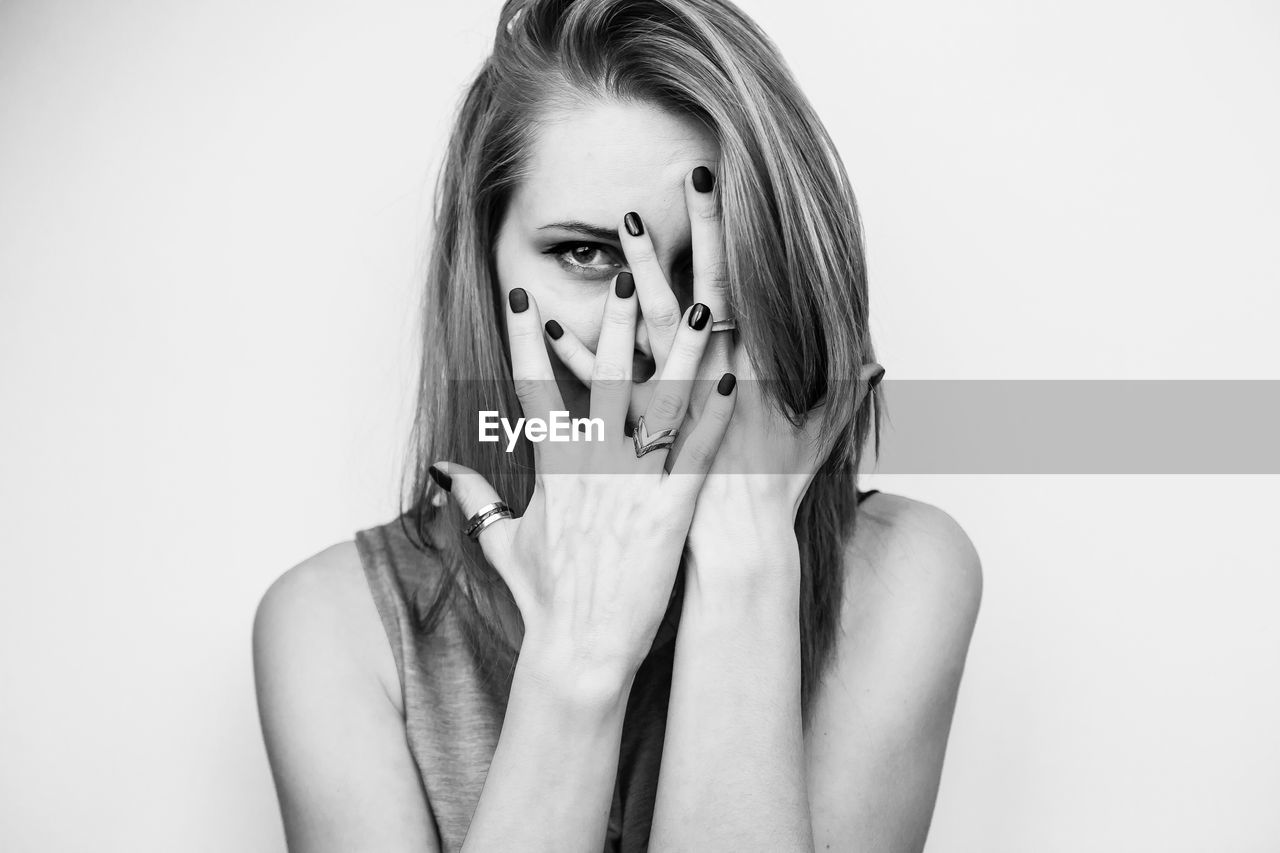 Portrait of woman with hands on face against white background