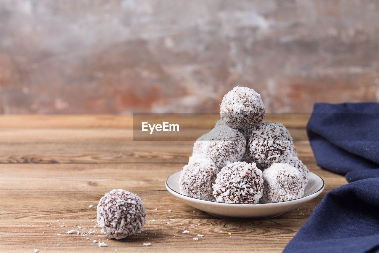 CLOSE-UP OF COOKIES ON TABLE AGAINST WOODEN WALL