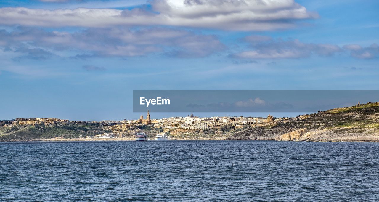 Sea by buildings against sky