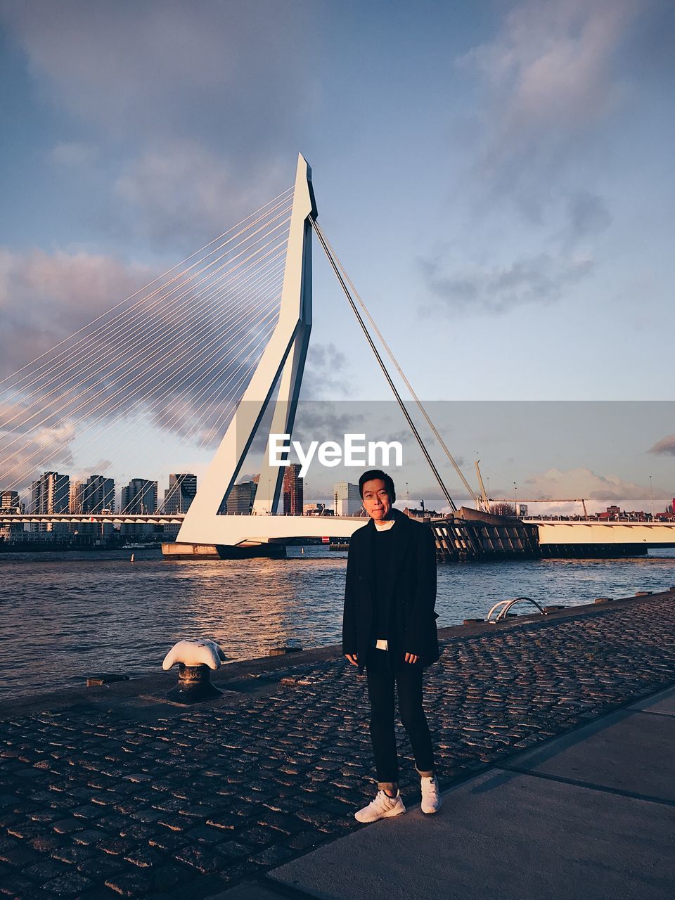 Portrait of man standing against bridge over river in city