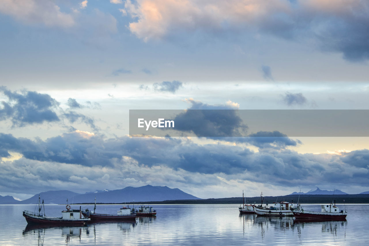 Sailboats moored in sea against sky