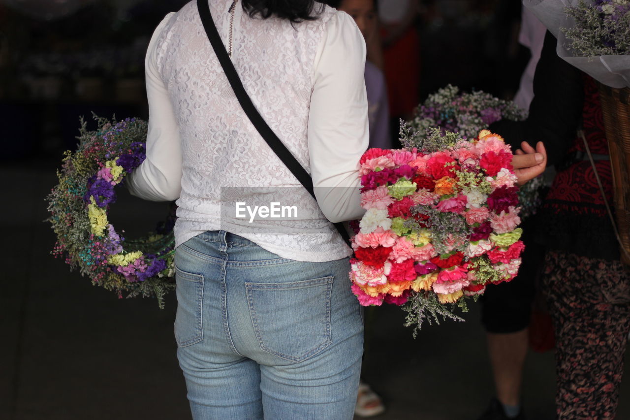 Midsection of florist carrying flower wreath decorations