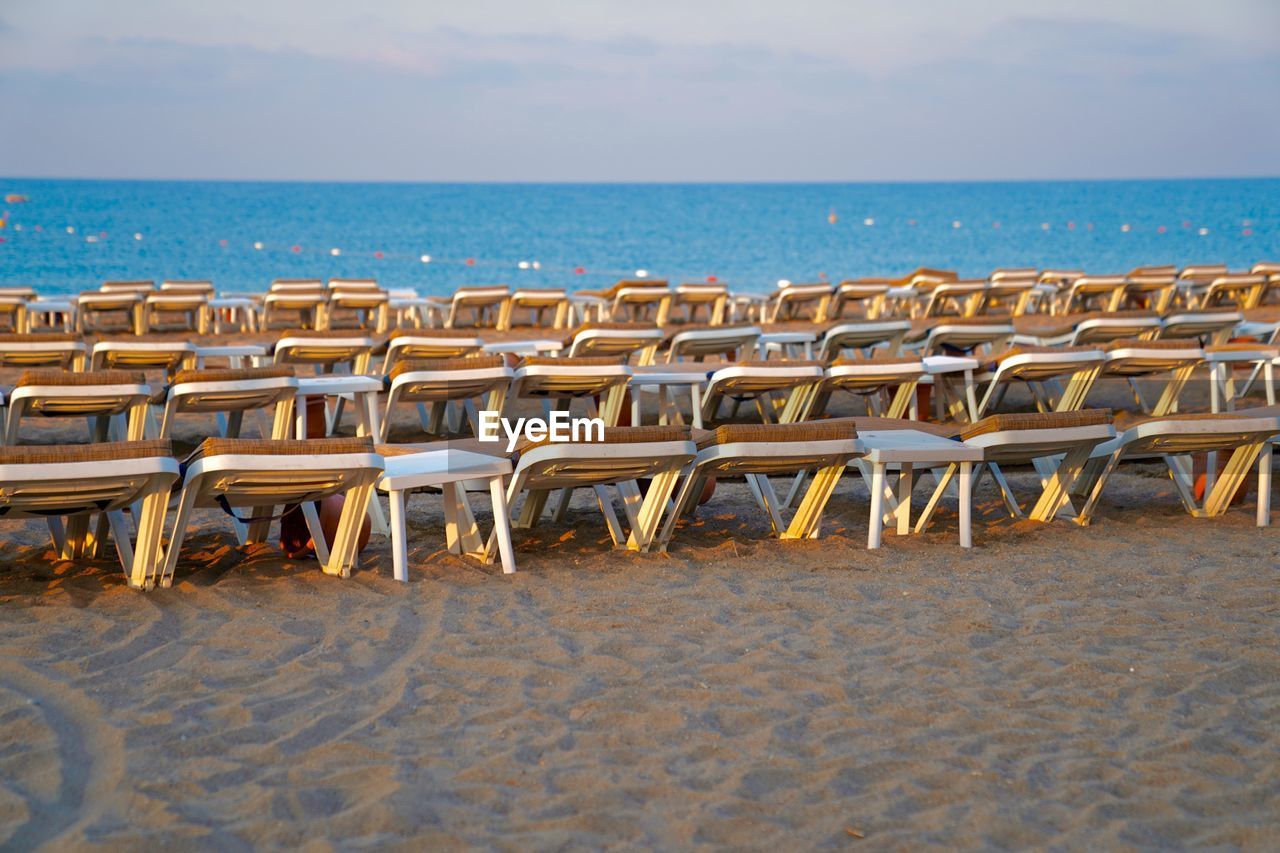 Chairs on beach against sky