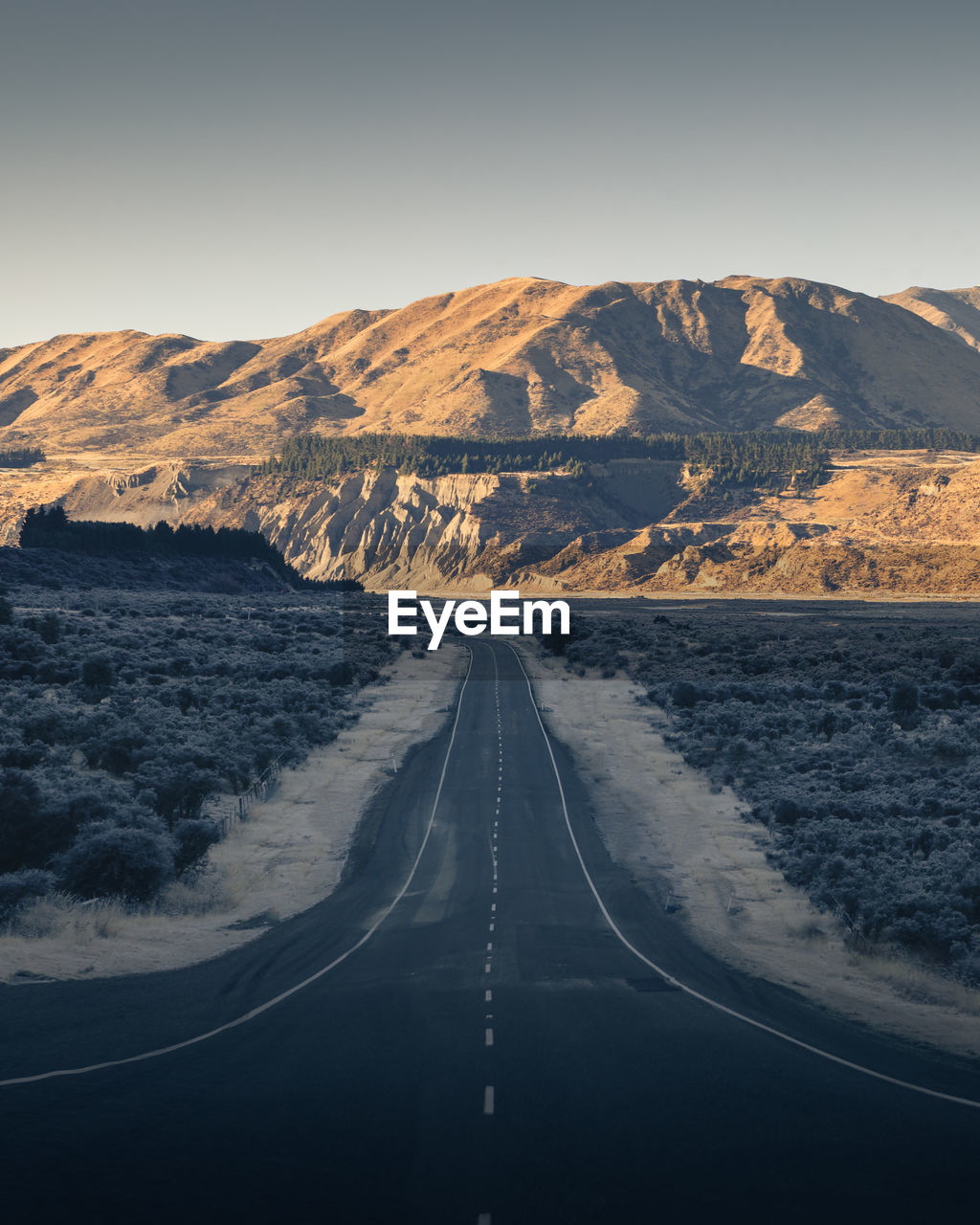 Scenic view of road by mountains against sky