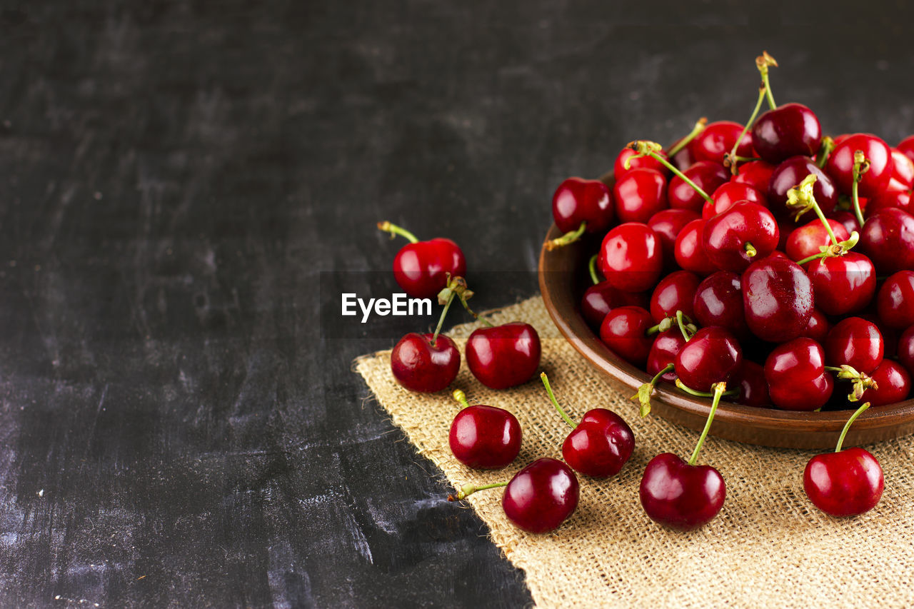 Fresh cherry on black wooden table. ripe sweet berries in the droplets of water