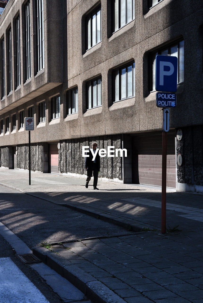 Rear view of man walking on street against buildings