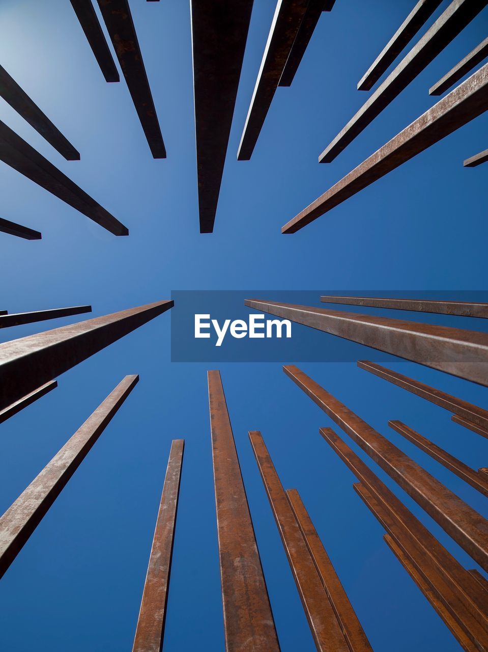 Low angle view of wooden post against clear blue sky