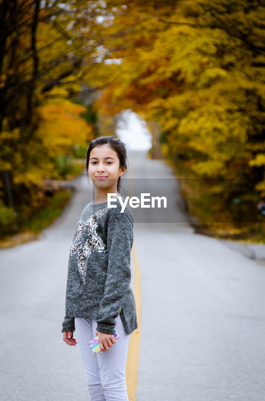 Portrait of cute girl standing on road during autumn