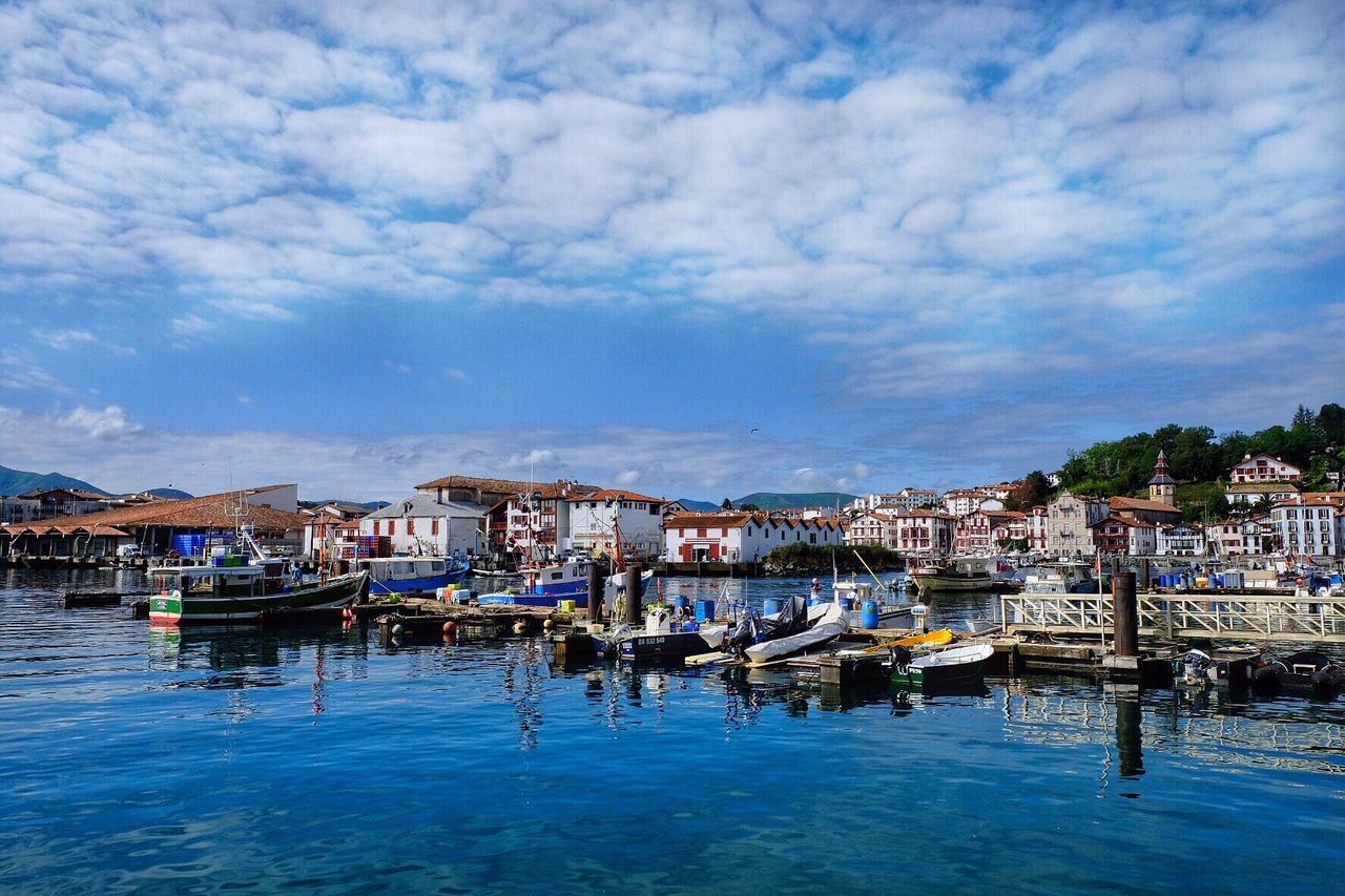 Houses by harbor against cloudy sky