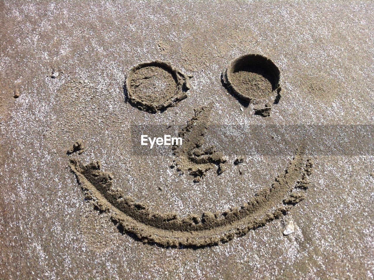 High angle view of anthropomorphic smiley face drawn on sand at beach