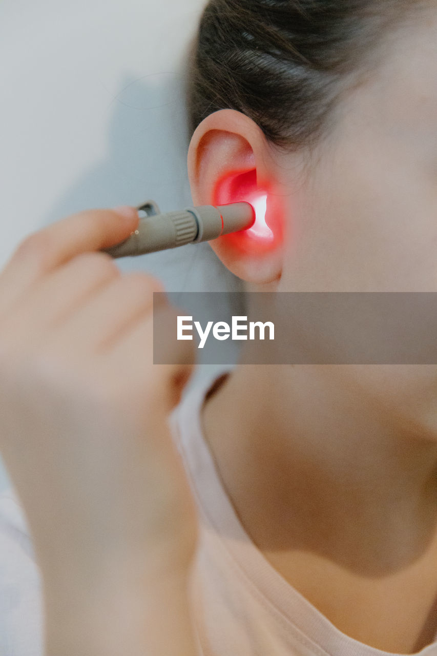 A girl treats her ear with an infrared light device.