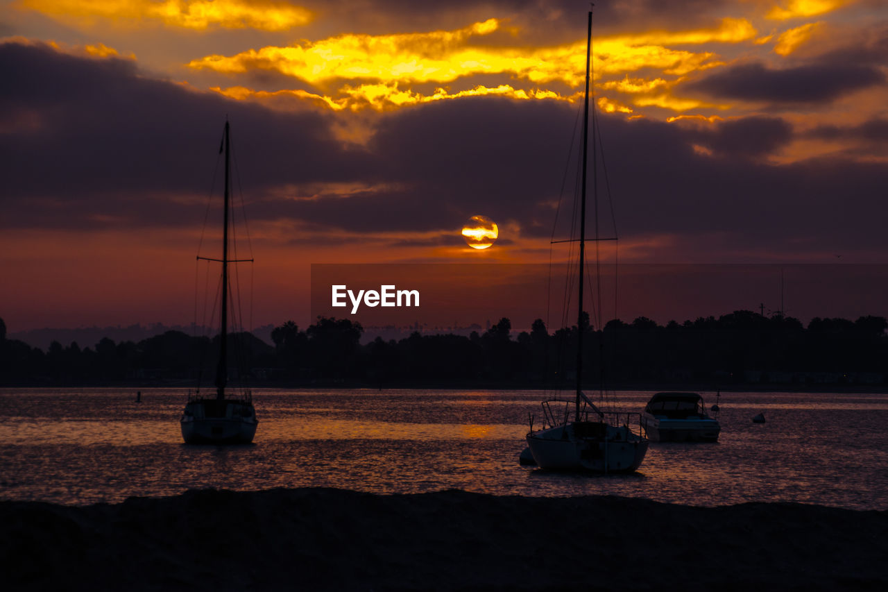 Sailboats on sea against sky during sunset