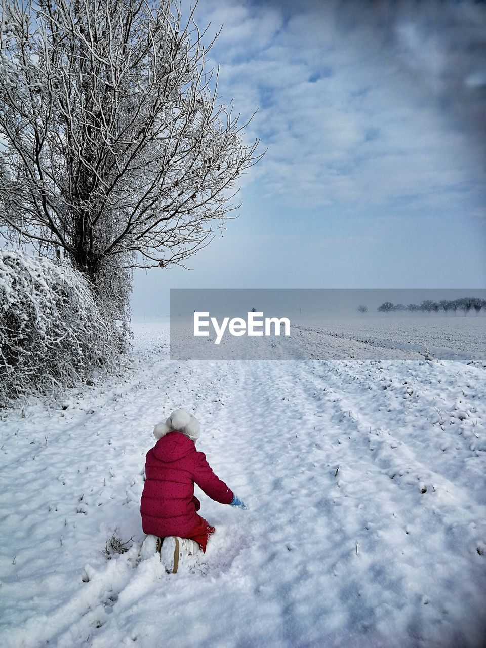 Girl on snow covered field against sky