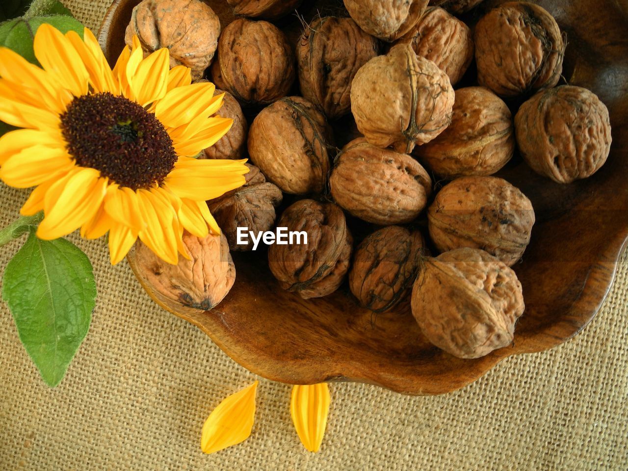 High angle view of walnuts in bowl by orange flower on tablecloth