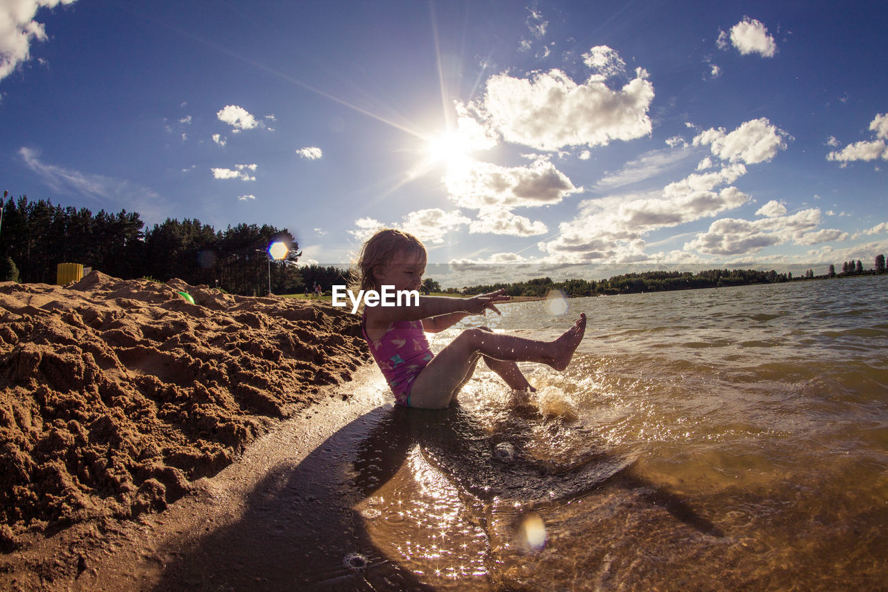 Girl playing at sea shore against sky