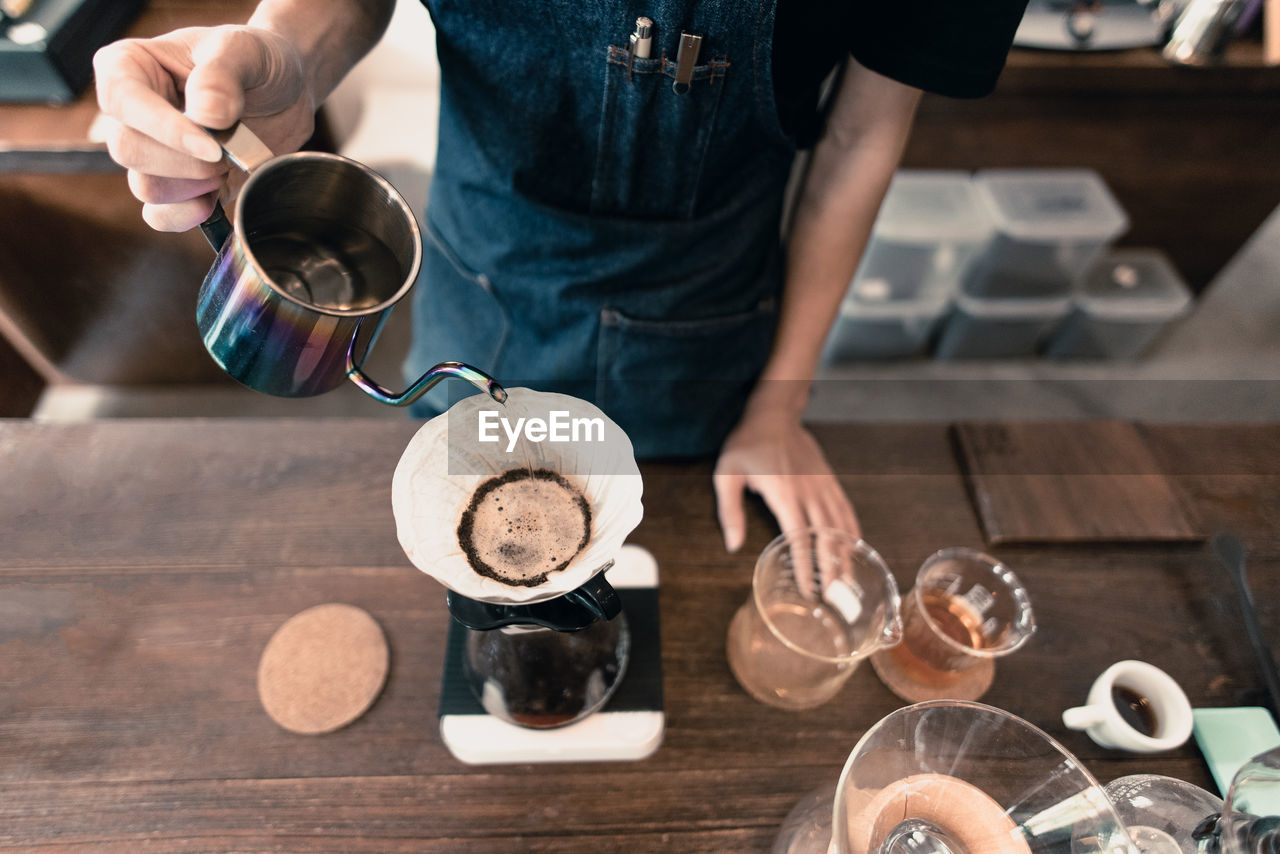 High angle view of man pouring water in coffee filter