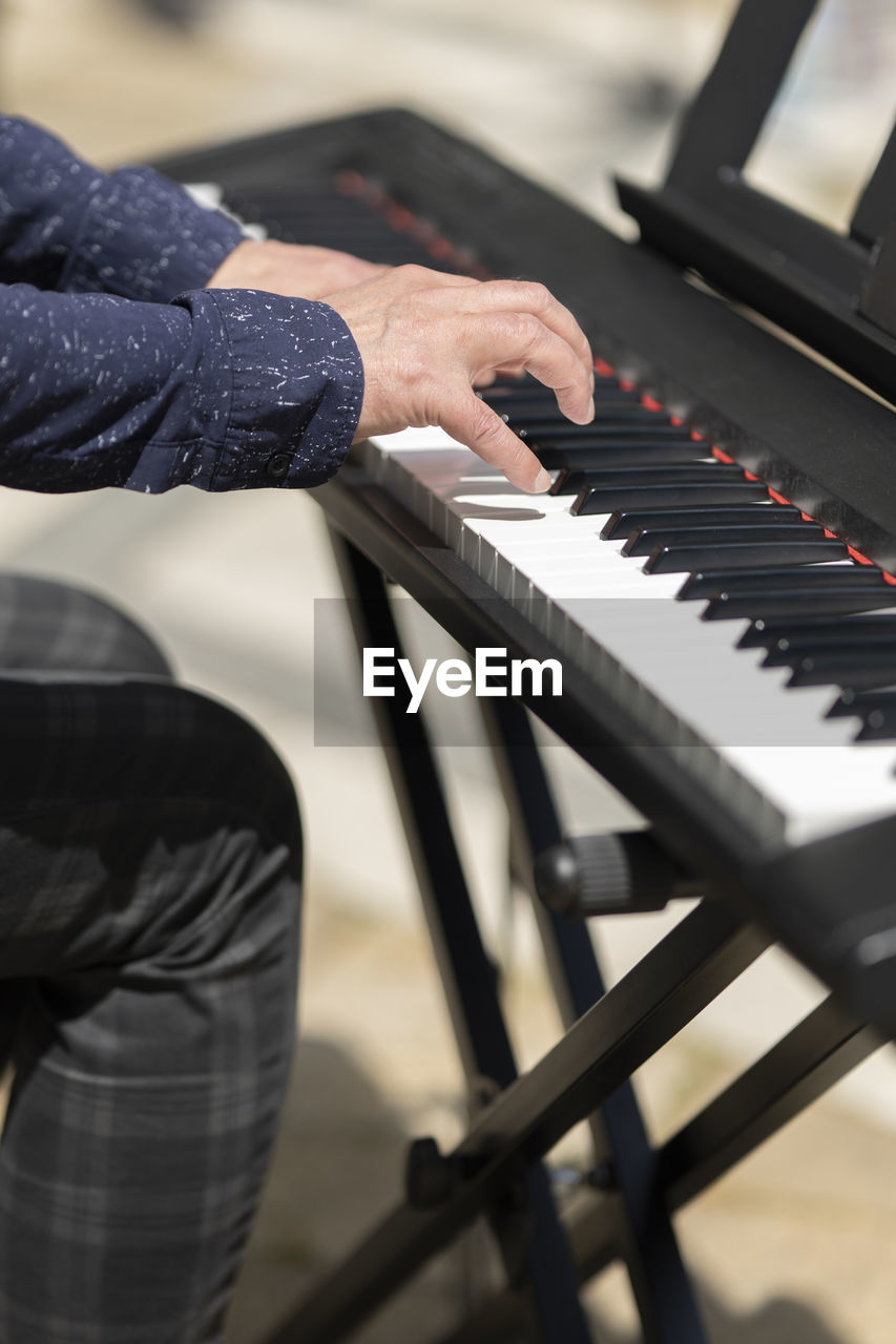 Cropped hand of man playing piano