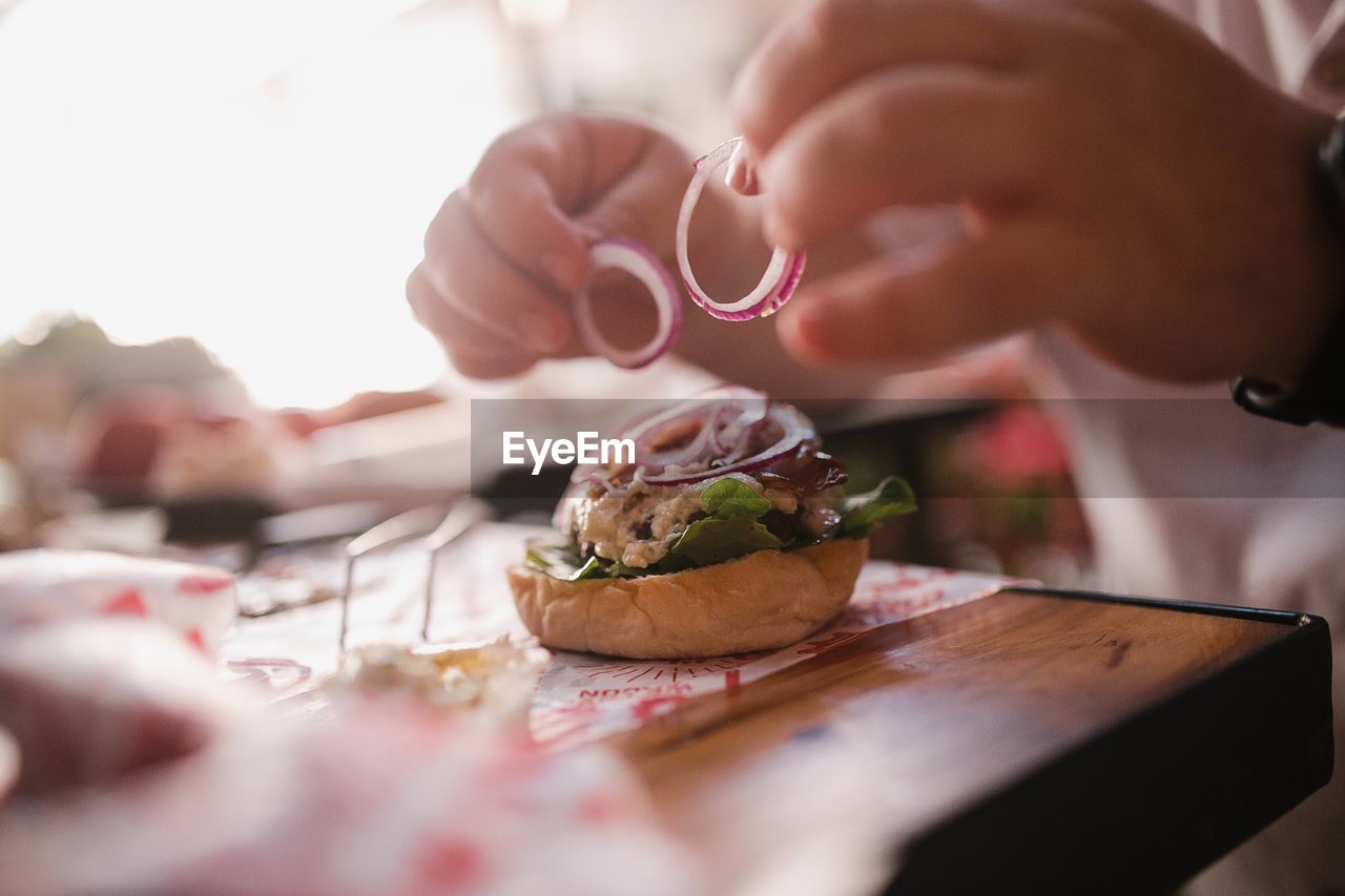 Close-up of hand preparing a burger