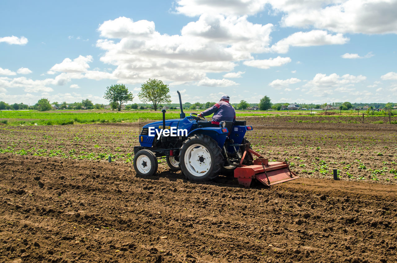 tractor, field, soil, agriculture, plough, rural scene, transportation, landscape, agricultural machinery, farm, land, agricultural equipment, sky, mode of transportation, occupation, nature, land vehicle, vehicle, machinery, farmer, environment, growth, working, cloud, adult, plant, one person, day, crop, dirt, plowed field, rural area, harvesting, men, plain, outdoors, driving, summer, food, copy space, sunlight