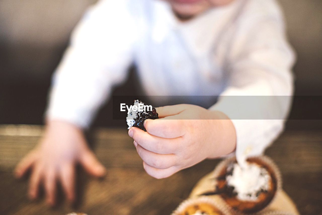 Midsection of child holding blackberry fruit