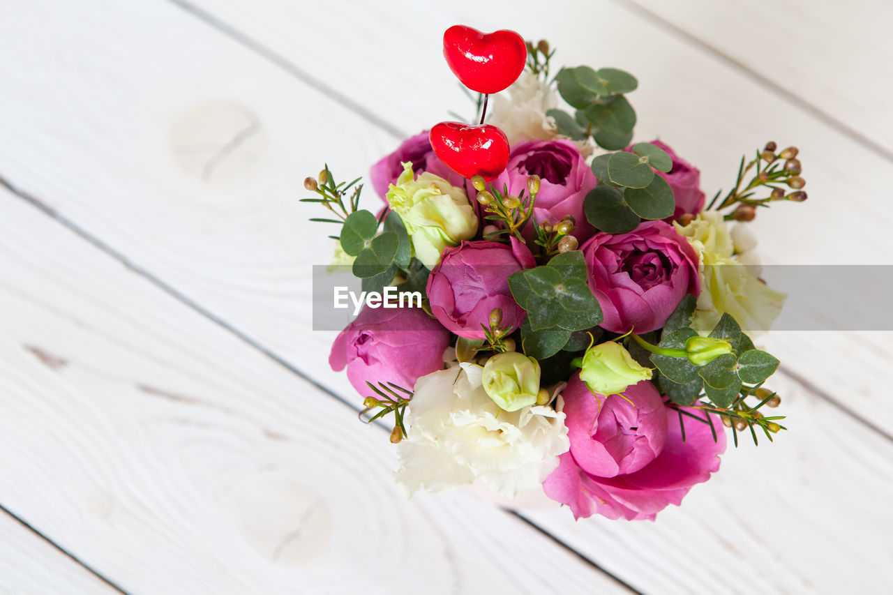 Creative flower bouquet on white wooden background. focus on flowers, background is blurred. 
