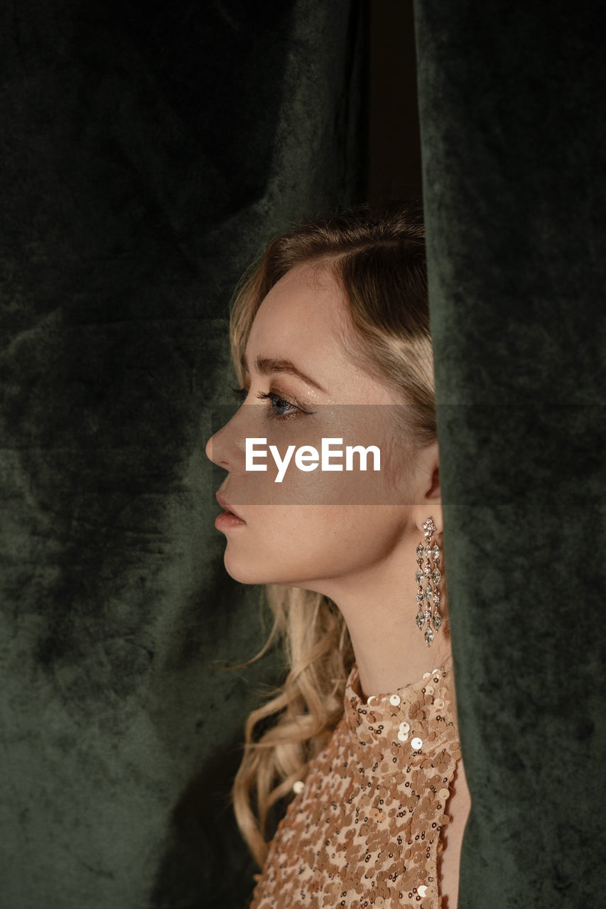 Fashionable young woman by curtain at new year's party