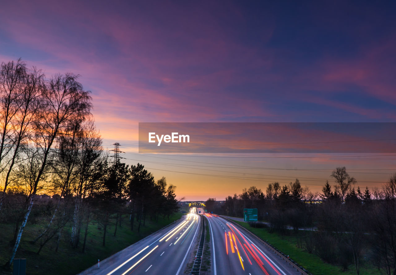 Cars on road against sky during sunset