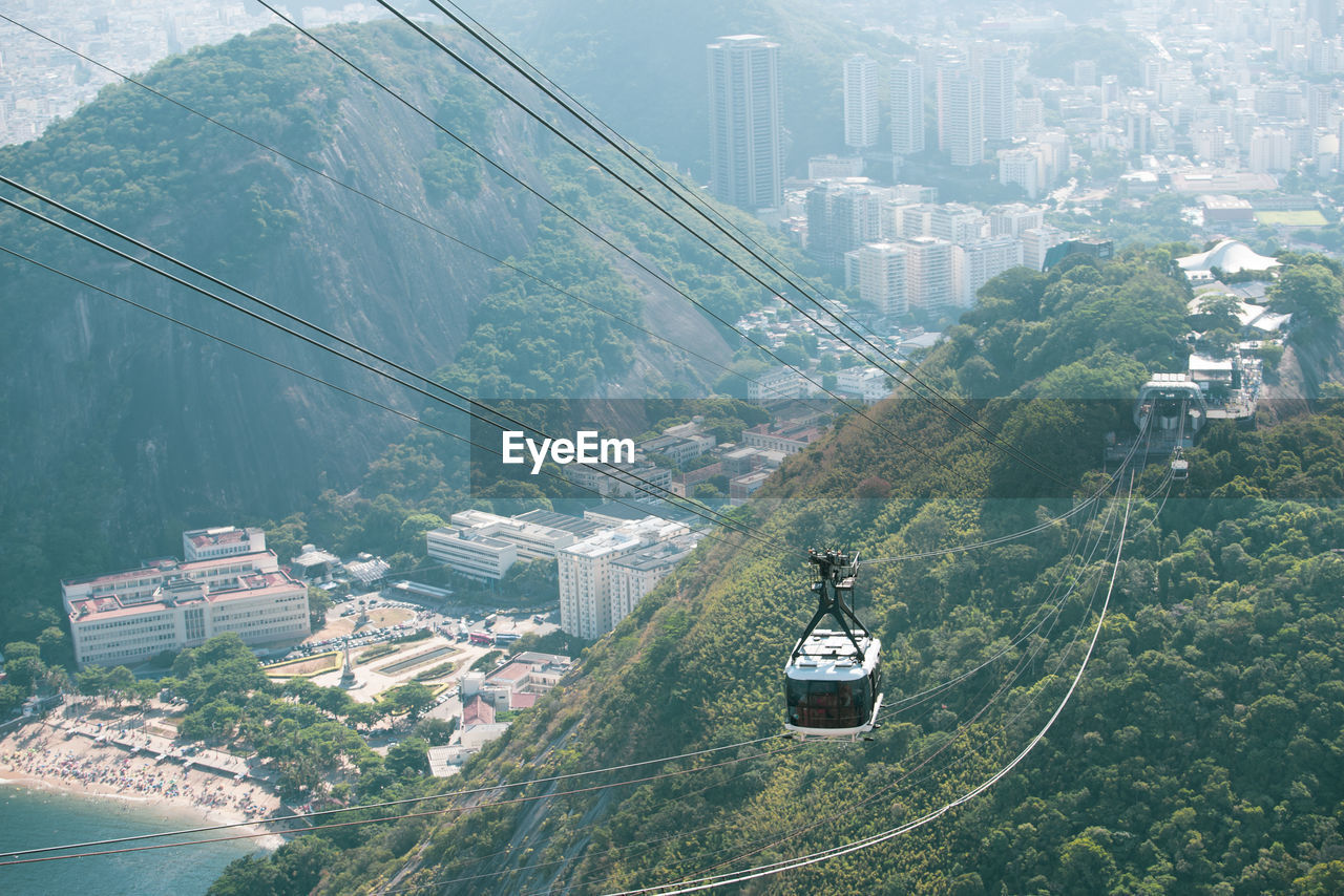 HIGH ANGLE VIEW OF OVERHEAD CABLE CAR AMIDST BUILDINGS