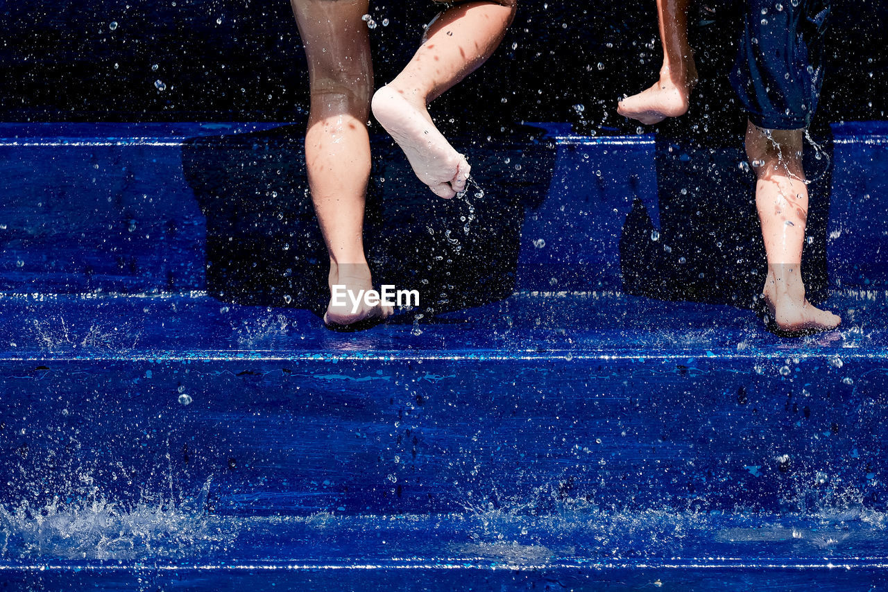 Low section of kids on blue steps amidst splashing water