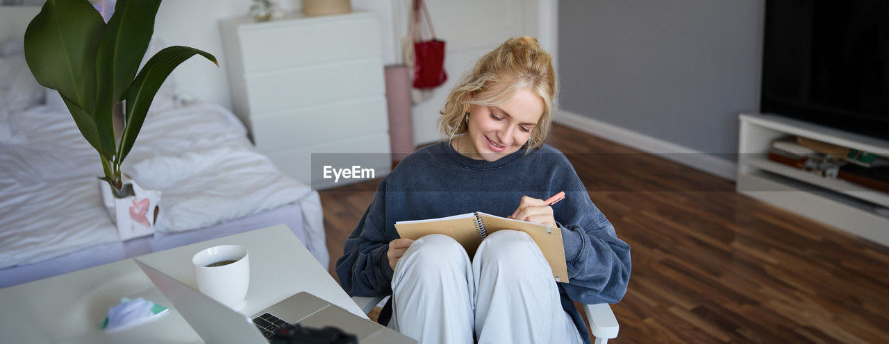 side view of woman sitting on bed at home