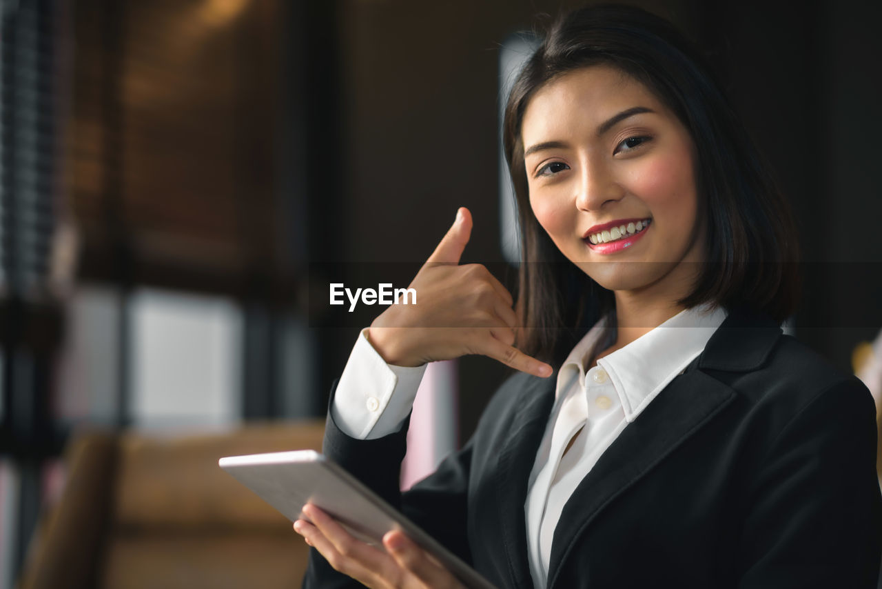 An asian businesswoman holding a tablet inviting her to come back.