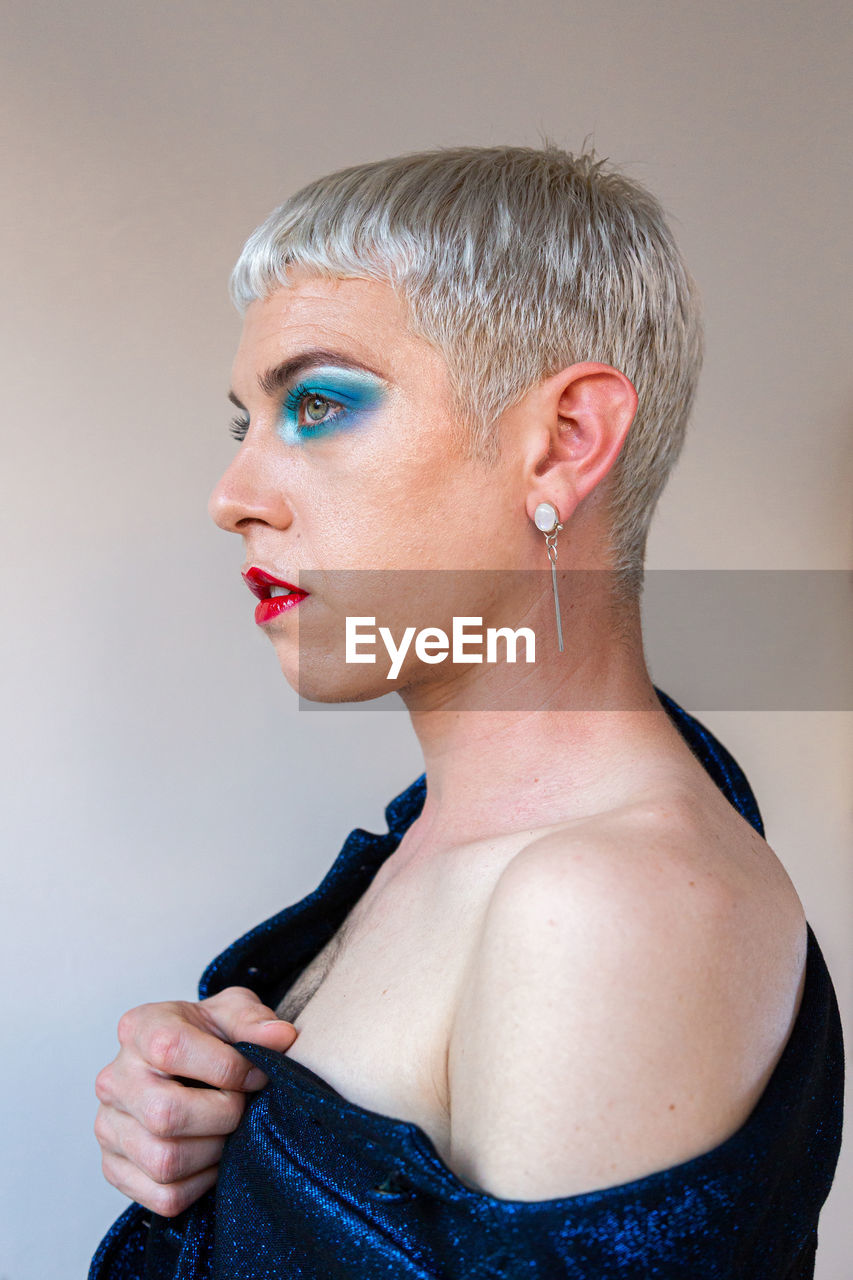 Portrait of young transgender man with makeup looking away