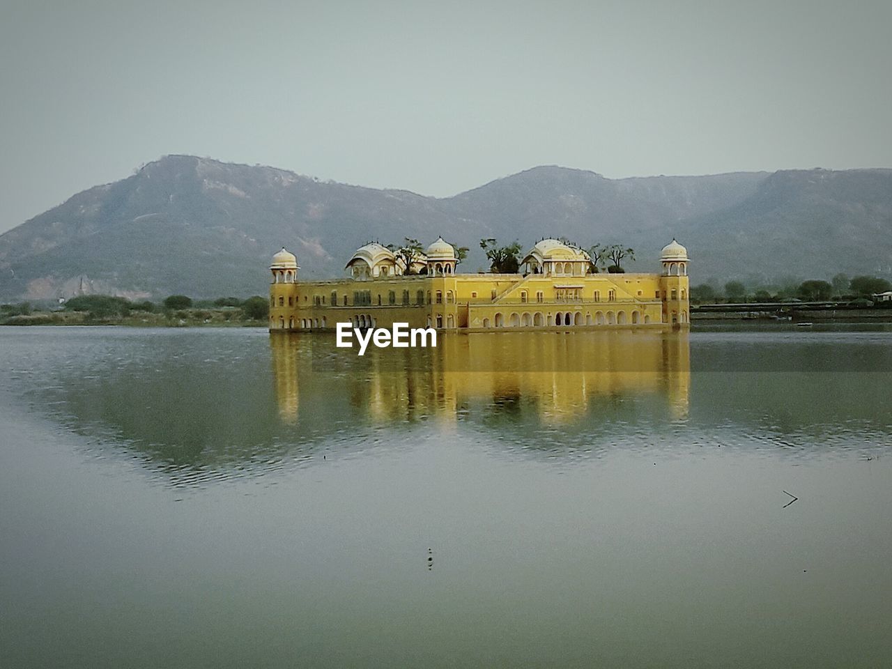 BUILT STRUCTURE BY LAKE AGAINST MOUNTAINS