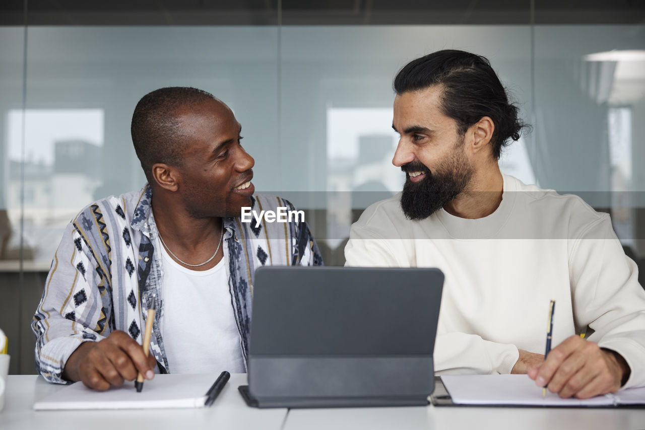 Smiling coworkers sitting at business meeting and looking at each other